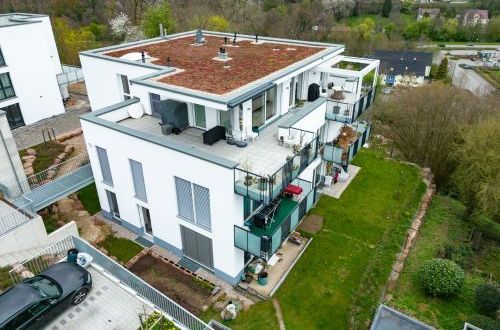 Modernes Mehrfamilienhaus mit Terrassen und Fahrrädern auf dem Balkon.