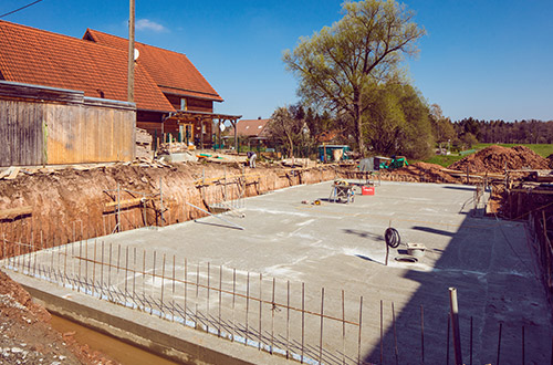 Fundament eines Gebäudes mit Stahlbewehrung und Versorgungsleitungen.