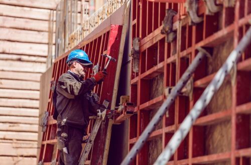 Bauarbeiter auf einer Gerüstwand bei Betonarbeiten.