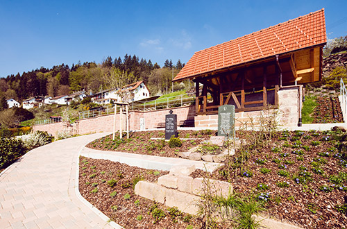 Ein kleiner Park mit Wegen, einer Sitzbank und einer kleinen Kapelle.
