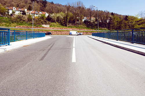 Leere Straße in einem ruhigen Vorort mit Brücke und Wohnhäuser.